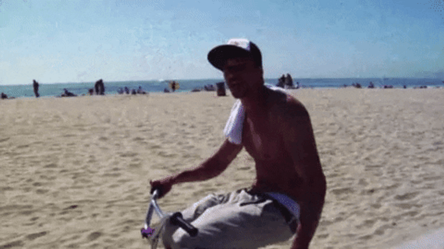 Topless Man Riding Bike By The Beach GIF
