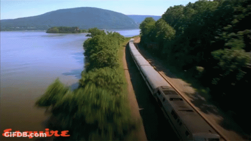 Train Going Down Tracks Next To Water With Esquire GIF