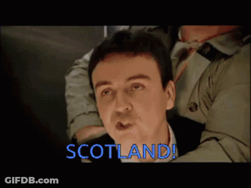 Trench Coat Man Held By Another Saying Scotland GIF