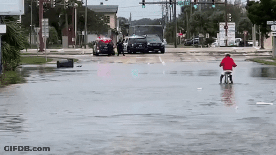 Tropical Storm Riding Bike In Flood GIF