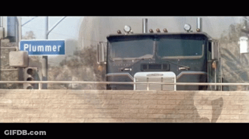 Truck Driving Next To Plummer Street Sign GIF