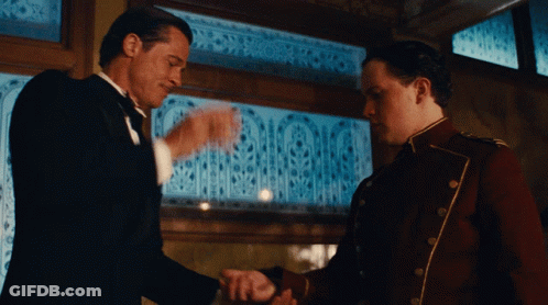 Tuxedo Man Shaking Hands With Red Uniform Man GIF