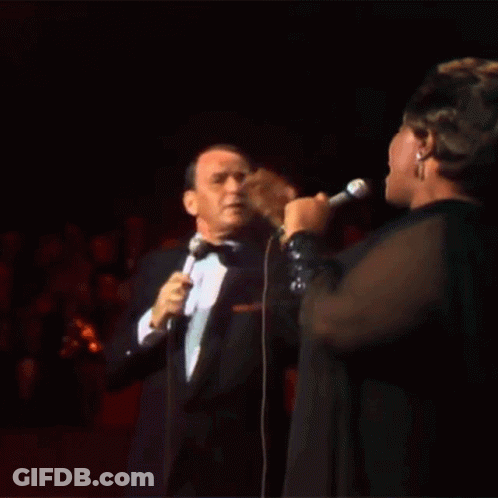 Tuxedo Man Sings To Woman In Black Dress GIF