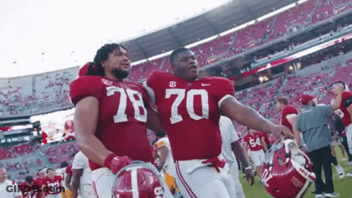 Two Alabama Football Players Wearing Number 78 And 70 Walk Off The Field GIF