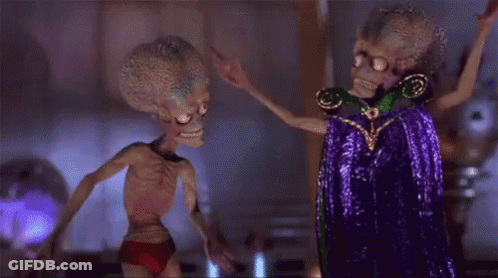 Two Aliens Standing Next To Each Other In Room GIF