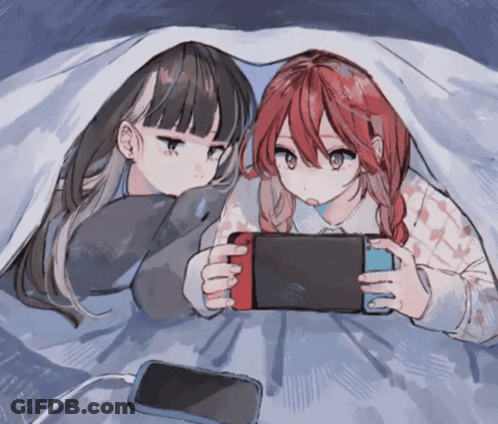 Two Anime Girls Laying Under A Blanket Playing A Game GIF
