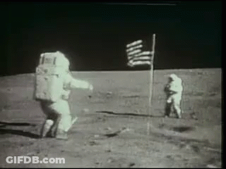 Two Astronauts Are Standing On The Moon Next To An American Flag . GIF