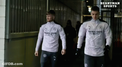 Two Athletes Wearing Marathon Shirts Walk Down A Hallway GIF