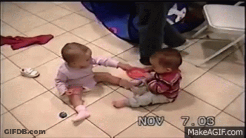 Two Babies Are Sitting On A Tiled Floor Playing With Toys . GIF