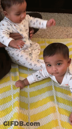 Two Baby Boys Laying On Yellow And White Blanket GIF
