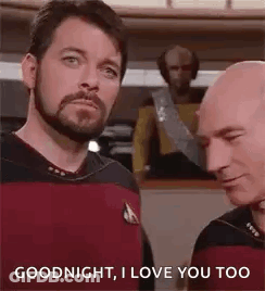 Two Bald Bearded Men Talking On Ship GIF