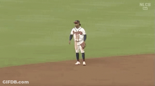 Two Baseball Players Are Shaking Hands On A Field . GIF