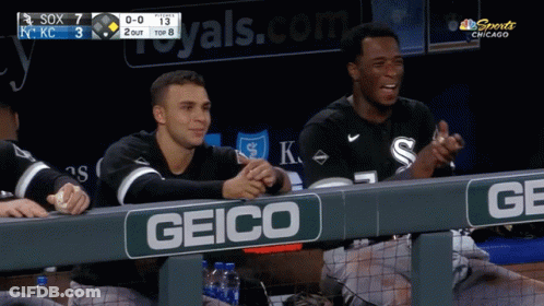 Two Baseball Players Are Sitting In The Dugout With A Geico Sign GIF