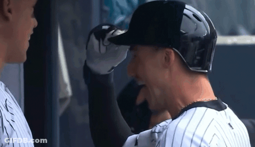 Two Baseball Players Are Standing Next To Each Other And One Is Wearing A Black Helmet . GIF