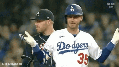 Two Baseball Players Are Standing Next To Each Other On A Field . One Of The Players Is Wearing A Dodgers Jersey . GIF
