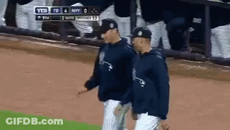 Two Baseball Players Are Walking On A Field With A Scoreboard Behind Them That Says Yes GIF