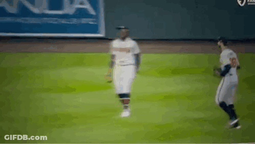 Two Baseball Players Are Walking On A Field . GIF