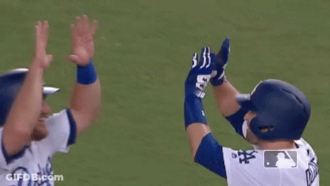 Two Baseball Players Hugging Each Other On The Field . GIF