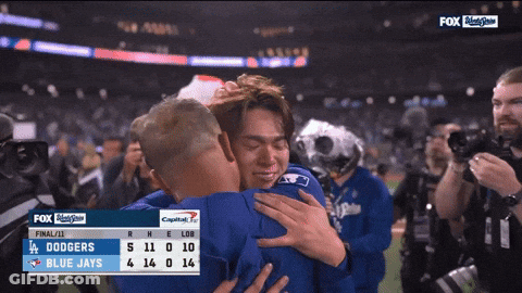 Two Baseball Players Hugging In Front Of Dodgers Scoreboard GIF