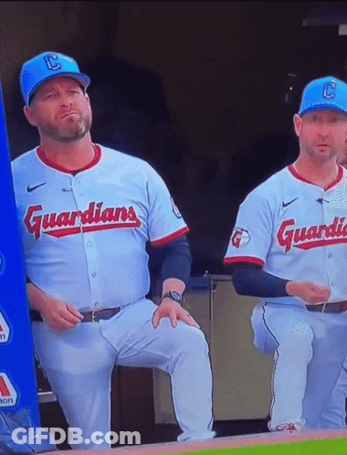 Two Baseball Players In Guardians Uniforms Sitting On Dugout GIF