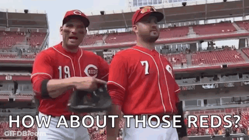 Two Baseball Players In Red Uniforms Are Standing Next To Each Other In A Stadium . GIF