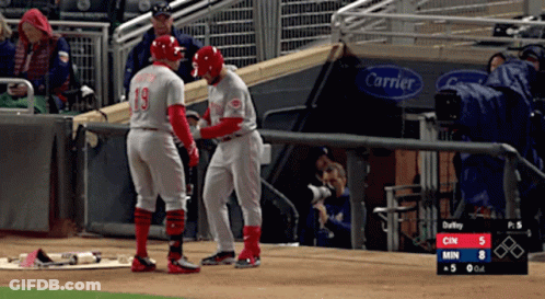 Two Baseball Players Standing On A Field With A Carrier Sign Behind Them GIF
