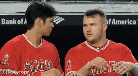 Two Baseball Players Wearing Angels Jerseys Are Talking To Each Other GIF
