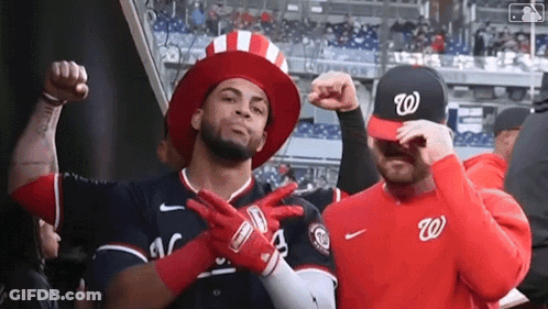 Two Baseball Players Wearing Hats And Gloves Are Posing For A Picture In A Stadium . GIF