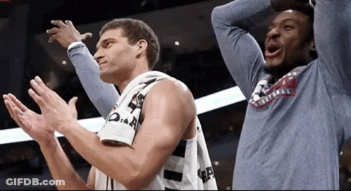 Two Basketball Players Are Clapping Their Hands And One Has A Shirt That Says Basketball On It GIF