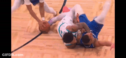 Two Basketball Players Are Fighting For The Ball On A Court During A Game . GIF