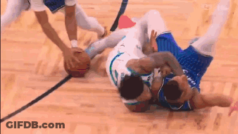Two Basketball Players Are Fighting Over A Basketball On A Wooden Court . GIF
