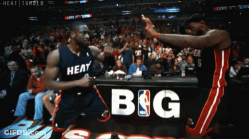 Two Basketball Players Are Giving Each Other A High Five In Front Of A Sign That Says Big GIF