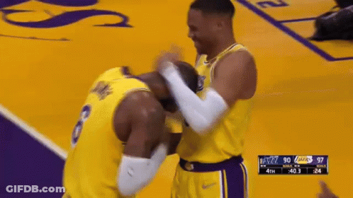 Two Basketball Players Are Hugging Each Other On A Court During A Game . GIF