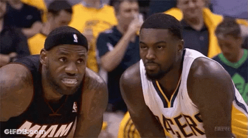 Two Basketball Players Are Looking At Each Other On The Court . One Of The Players Is Wearing A Miami Jersey . GIF