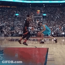 Two Basketball Players Are Playing A Game Of Basketball In Front Of A Crowd . GIF