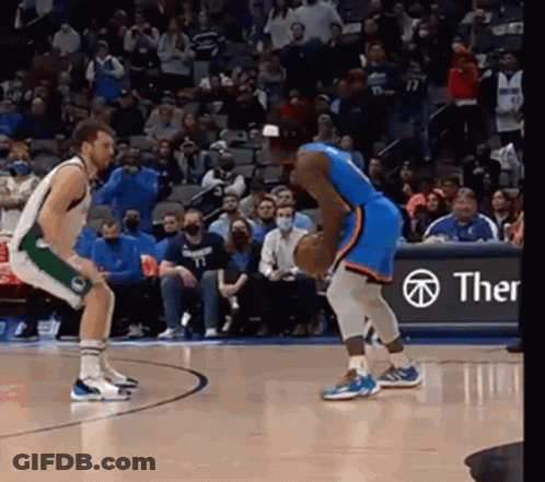 Two Basketball Players Are Playing A Game Of Basketball On A Court With A Crowd Watching . GIF