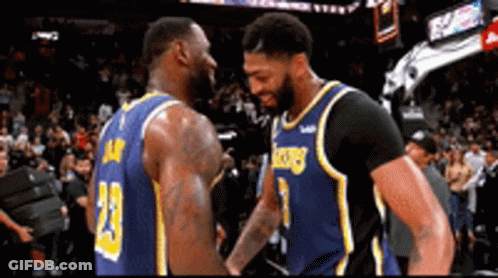 Two Basketball Players Are Shaking Hands During A Game In Front Of A Crowd . GIF