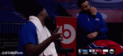 Two Basketball Players Are Sitting In Front Of A Bose Sign GIF