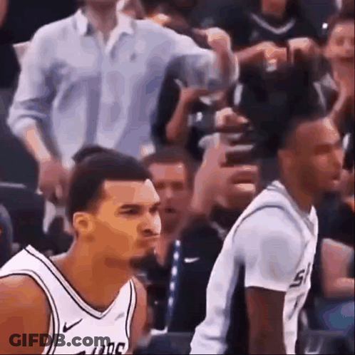 Two Basketball Players Are Sitting In The Stands During A Game And One Of Them Is Making A Funny Face . GIF