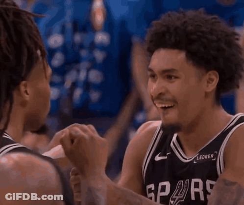 Two Basketball Players Are Talking To Each Other In Front Of A Crowd With A Sign That Says Cest On It GIF