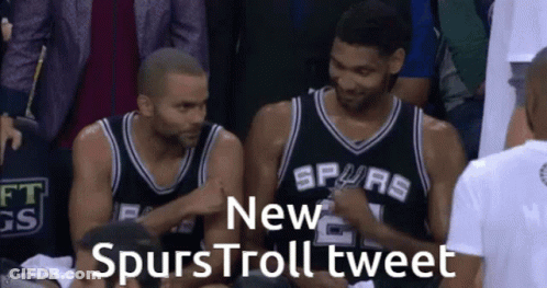 Two Basketball Players Wearing Spurs Jerseys Are Sitting In A Stadium GIF