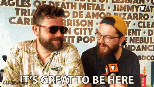Two Bearded Men In Front Of Sign It's Great To Be Here GIF