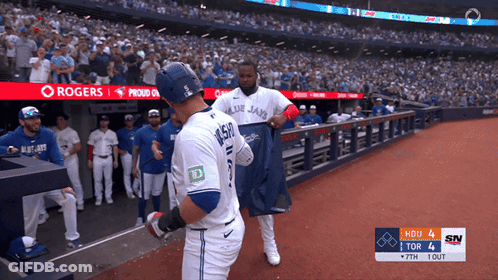 Two Blue Jays Baseball Players In Front Of Rogers Banner GIF