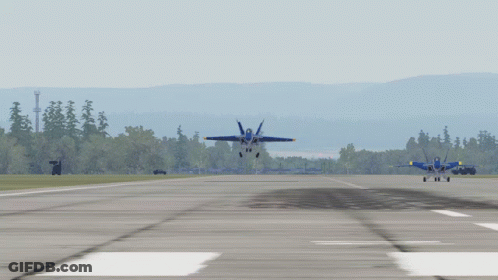 Two Blue Jets Are Taking Off From A Runway With Trees In The Background GIF