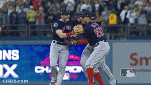 Two Boston Red Sox Players Are Hugging Each Other On The Field GIF