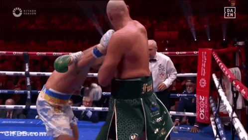 Two Boxers Are Fighting In A Boxing Ring While A Referee Looks On . GIF
