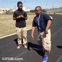 Two Boys Are Standing On A Track And One Of Them Has A Lanyard Around His Neck GIF