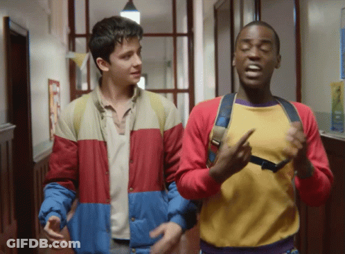 Two Boys Are Walking Down A Hallway And One Of Them Is Wearing A Yellow Shirt GIF