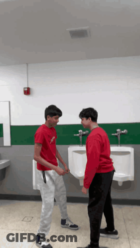Two Boys In Bathroom One Wearing Red Jesus Shirt GIF