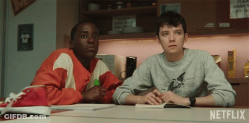 Two Boys Sit At A Table In Front Of A Netflix Sign GIF